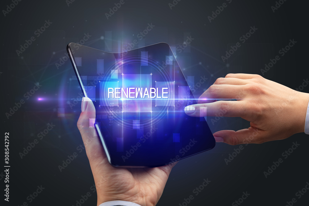 Businessman holding a foldable smartphone with RENEWABLE inscription, new technology concept Businessman holding a foldable smartphone with RENEWABLE inscription, new technology concept