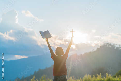 Woman praying to God with a cross on a sunrise background Women pray for the blessing of God for a better life.