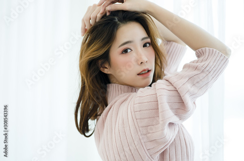 Portrait of inspired beautiful Asian lady in warm knitted sweater pink clothes at home.Concept woman lifestyle and winter. Autumn  winter season.