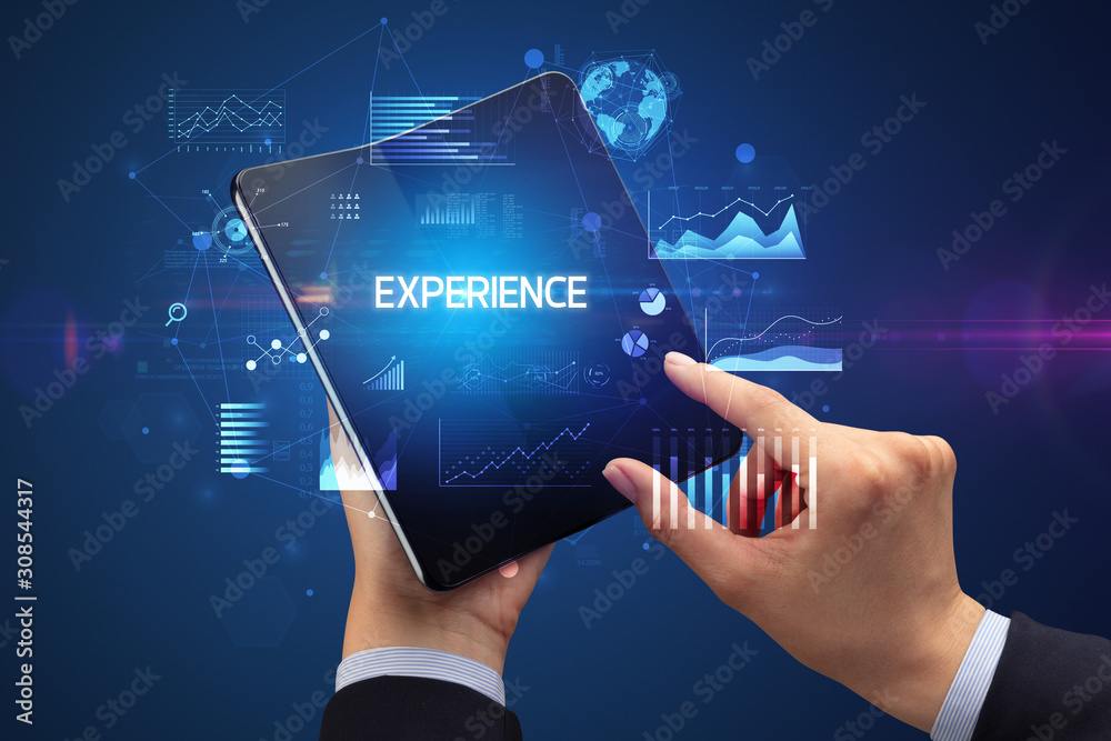 Businessman holding a foldable smartphone with EXPERIENCE inscription, successful business concept Businessman holding a foldable smartphone with EXPERIENCE inscription, successful business concept