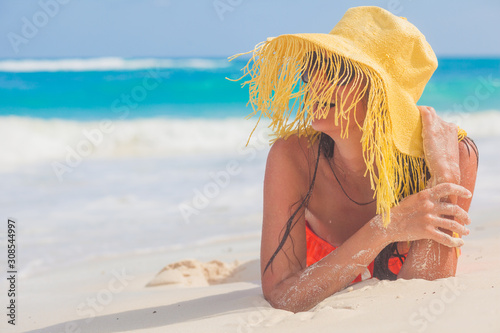 Canvas Print Young woman in bikini and straw hat relaxing at white caribbean beach