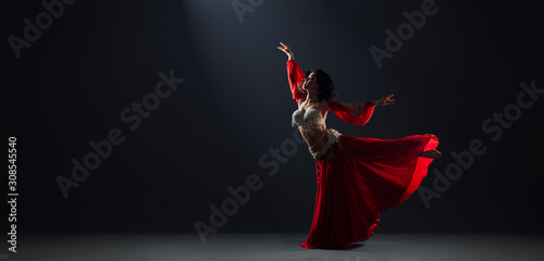 Fotografia Woman in red arabic dress dancing oriental dances arabesque pose