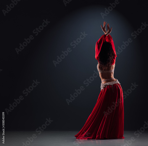 Photographie beautiful black-haired girl in a red ethnic dress on stage dances oriental danci