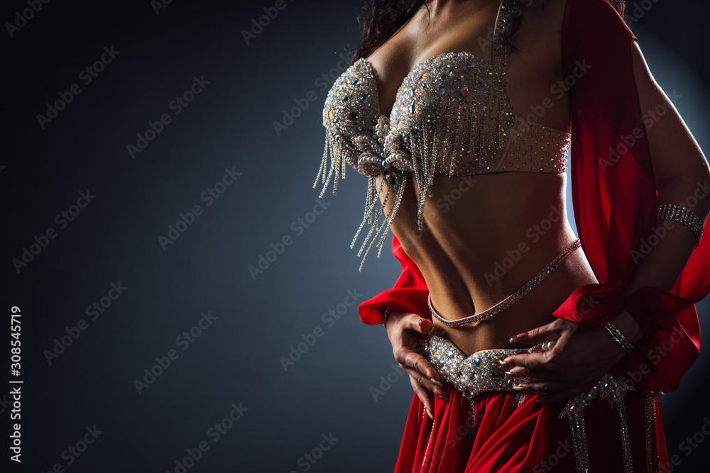 Beautiful belly dance of a girl in a red decorated ethnic dress in dark - obrazy, fototapety, plakaty 