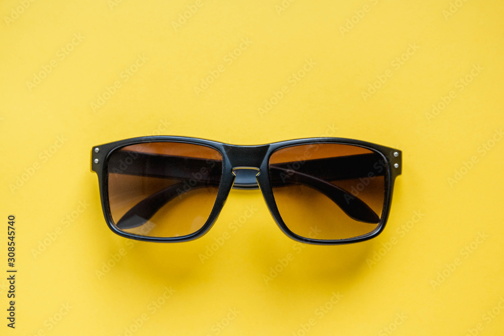 Sunglasses in a black frame on yellow background. Top view. Copy, empty space for text Sunglasses in a black frame on yellow background. Top view. Copy, empty space for text