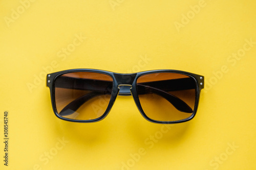 Sunglasses in a black frame on yellow background. Top view. Copy, empty space for text