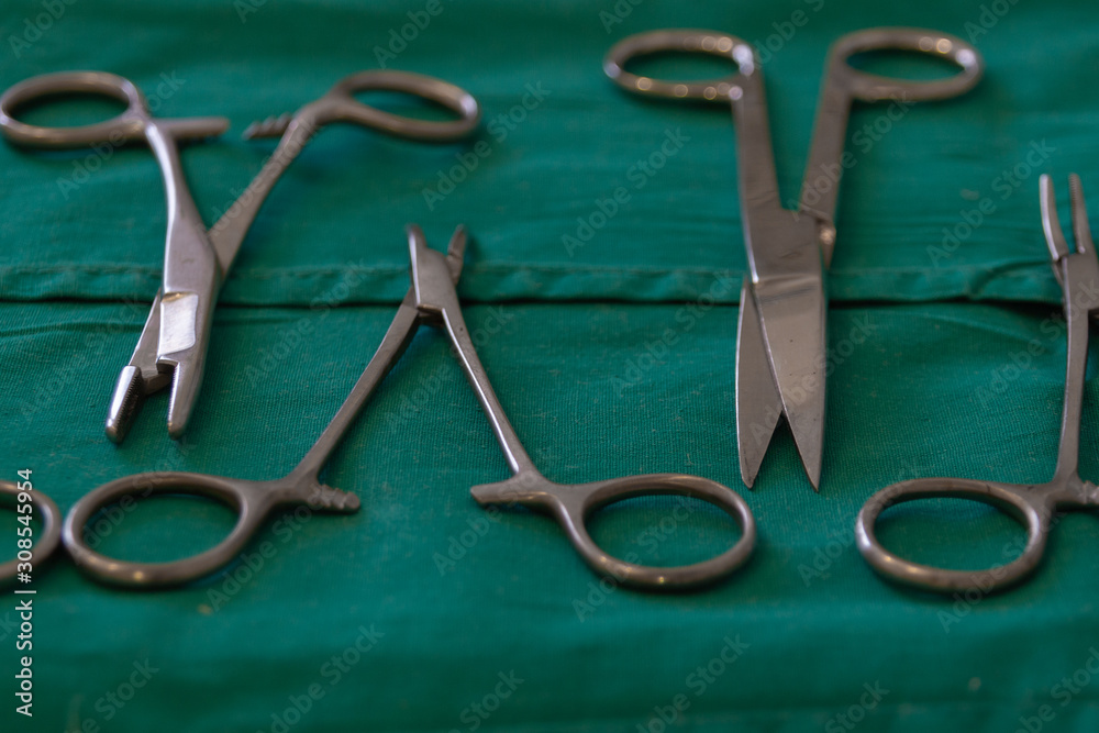Surgical and medical equipment in the operating room. Sterile scissors, hemostat, needle holder on green background. picture taken with a shallow depth of field. Surgical and medical equipment in the operating room. Sterile scissors, hemostat, needle holder on green background. picture taken with a shallow depth of field.