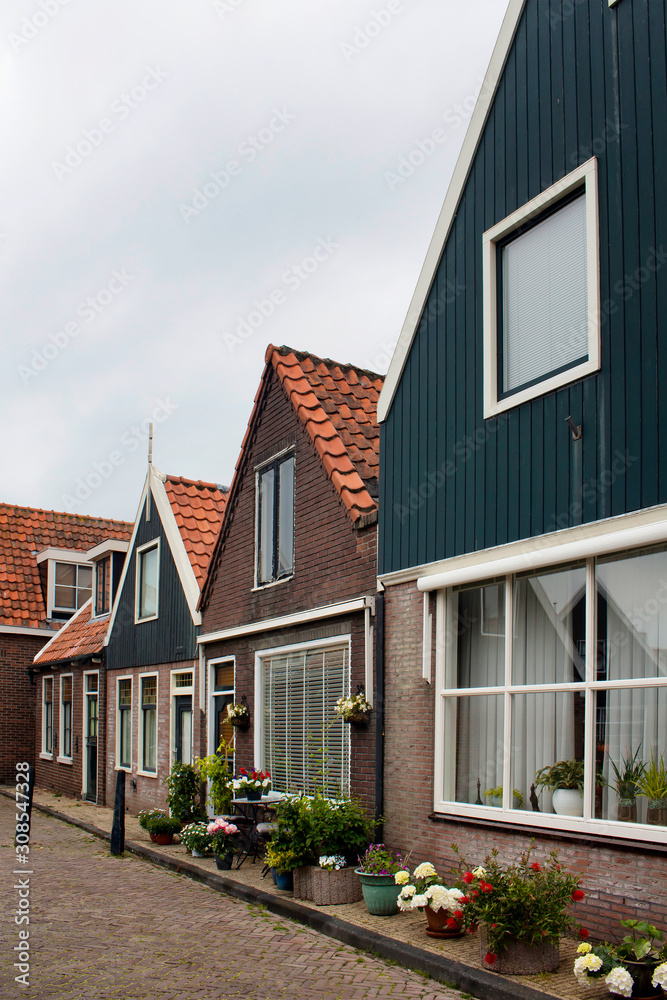 View of historical and traditional houses, plants and flowers in Volendam. It is a Dutch town, northeast of Amsterdam. It’s known for its colorful wooden houses and the old fishing boats.