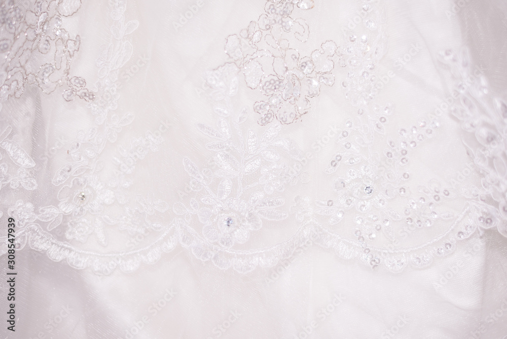 Fototapeta premium White lace fabric with sequins, sequins. Delicate wedding background. Openwork
