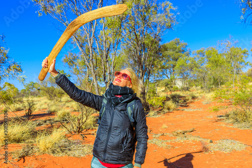 Happy tourist woman holding an aboriginal weapon of boomerang used by Luritja and Pertame people in Central Australia, Northern Territory