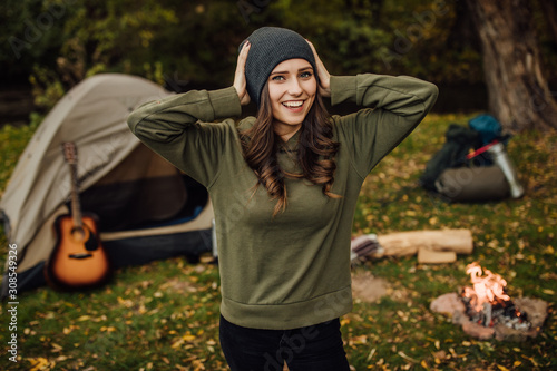 Portrait of young beautiful female tourist in the forest near tent and sleeping bag.