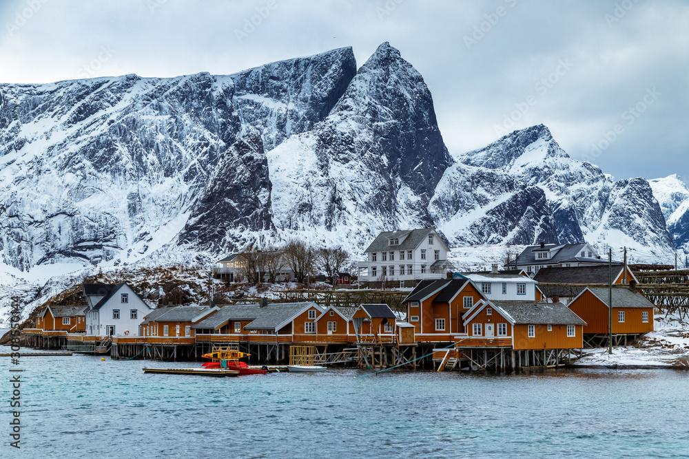 Beautiful winter landscape on Lofoten islands with traditional fishing village, yellow rorbu houses and mountains. Blue hour. Travel Norway.