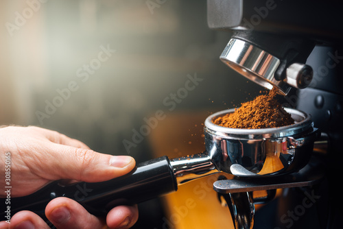 Papier peint ground coffee pouring into a portafilter with a grinder