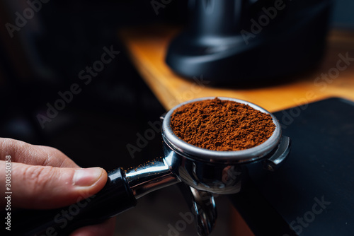 portafilter full of ground coffee in a hand photo