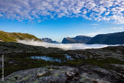 Wonderful view of the top of the mountain on a background of blue sky and fog. Traveling in Norway