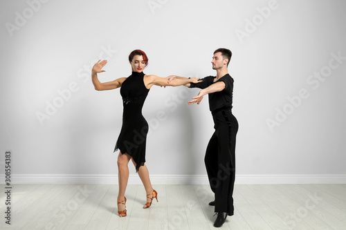 Fototapeta Naklejka Na Ścianę i Meble -  Beautiful young couple dancing near light wall