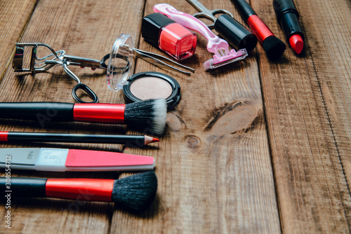 A set of cosmetics on a wooden table. The concept of doing makeup, caring for the appearance of women. Applying brushes, eye shadows, powder.