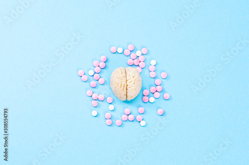 Brain on a blue background with white and pink pills. Some pills for the brain. Symbolical for medicines, psychopharmaceuticals, nootropics and other medicines. Medicine. Brain treatment