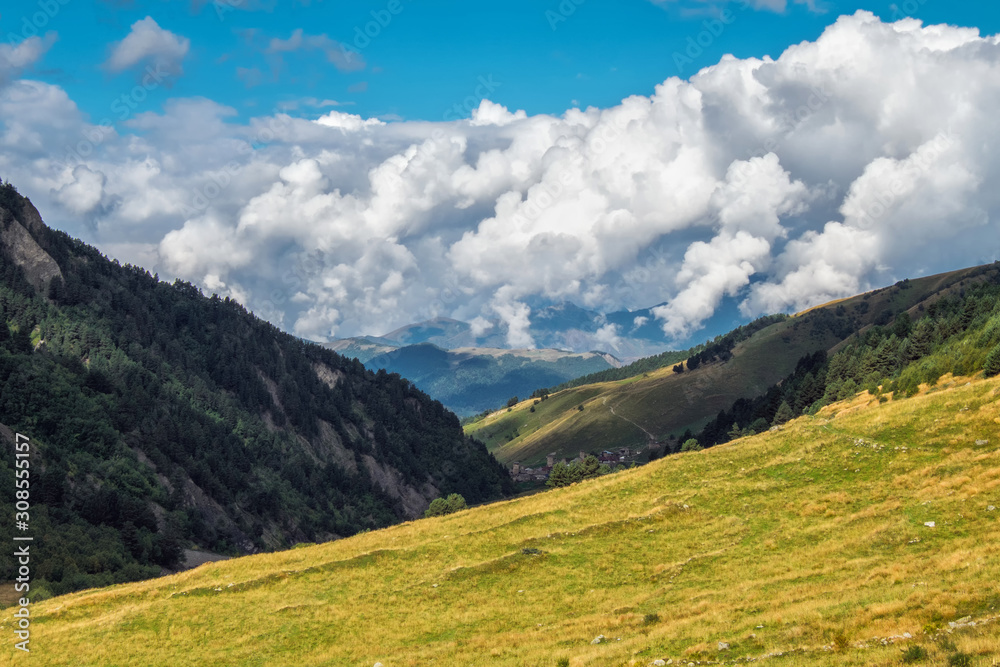 Beautiful early autumn landscape in mountains of Svaneti Georgia with big clouds on a blue sky