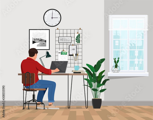 A freelancer man works behind a laptop. Home office workplace.