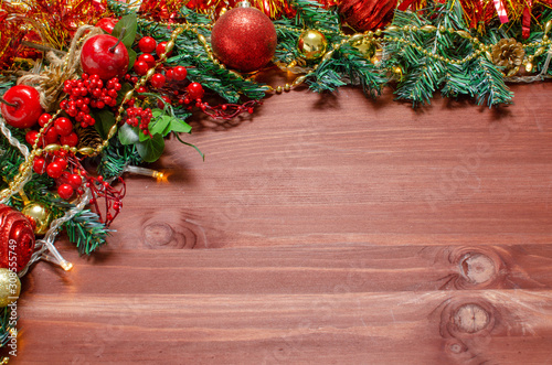 Christmas toys, decorations, cones, a garland and fir branches are laid out on the edge of a dark wood background. Copyspace in the center. Christmas card concept. Top view, close up, flat top.