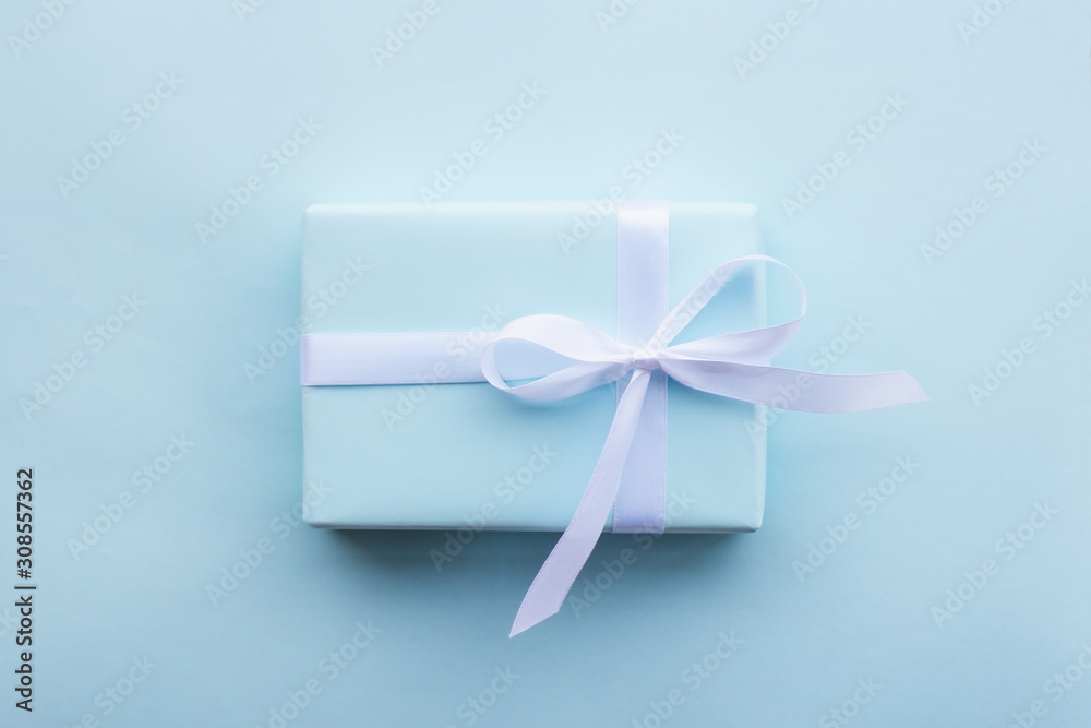 gift in a blue box tied with a white ribbon on a blue background top view gift in a blue box tied with a white ribbon on a blue background top view