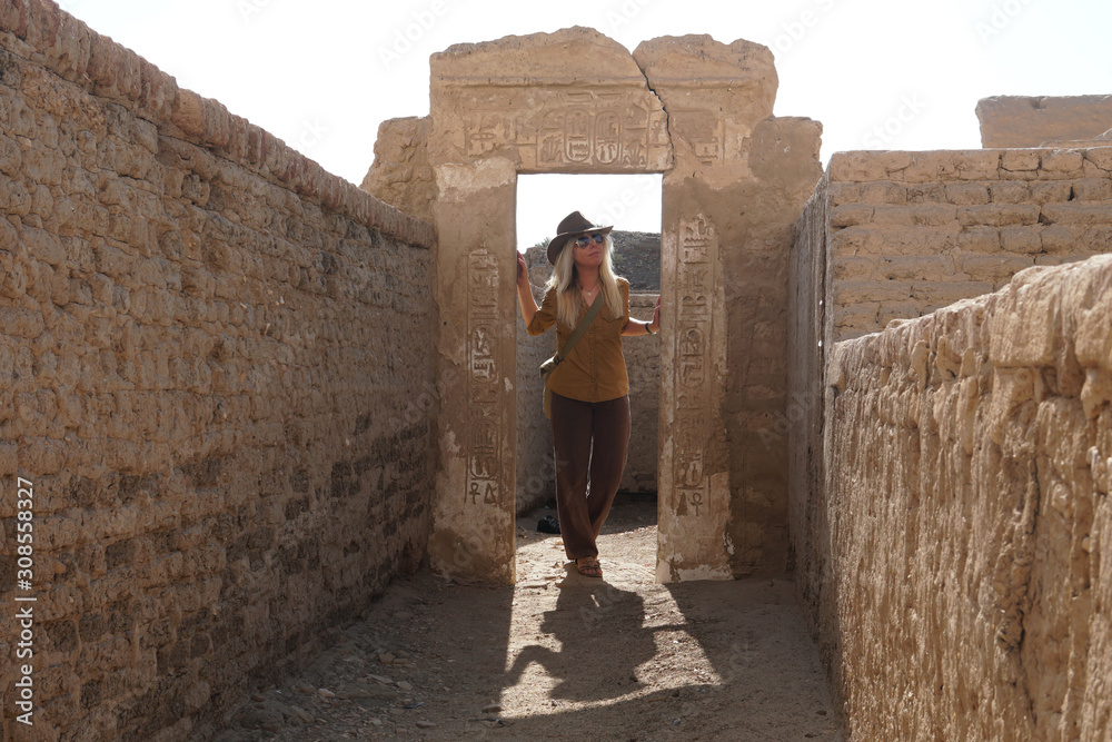 blonde Frau als Tourist im Tempel von Ramses III. betrachtet interessiert die Ruinen