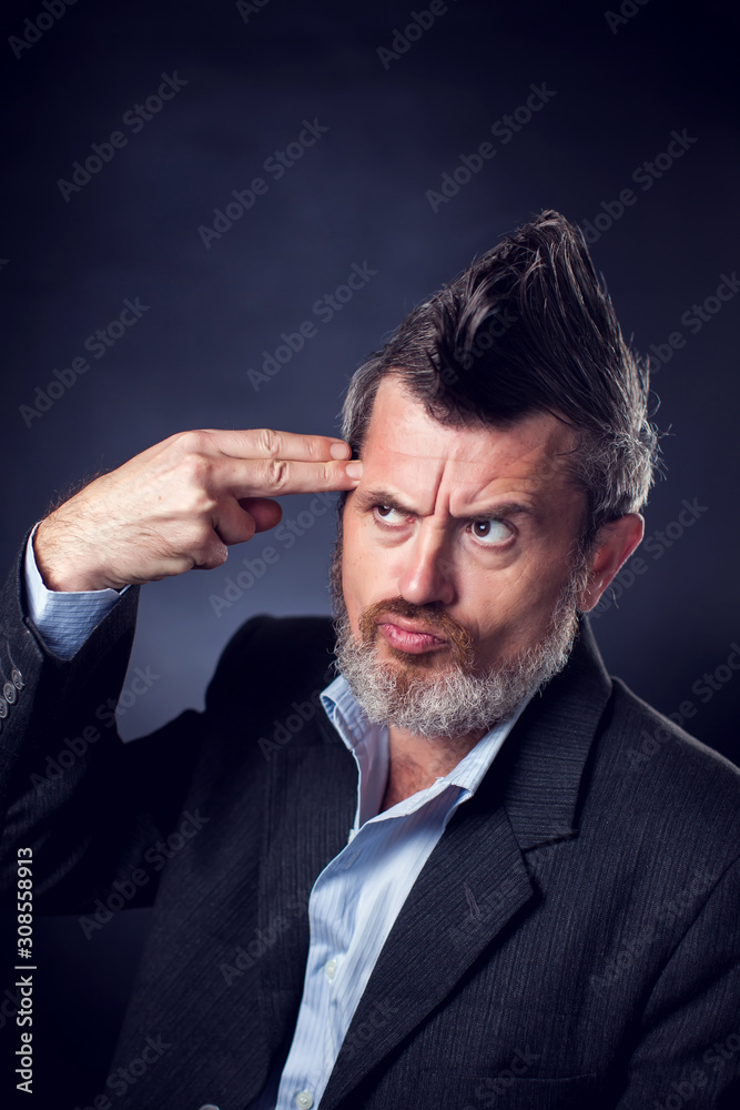 A portrait of bearded man with iroquois wearing suit showing gun gesture. People and emotions concept