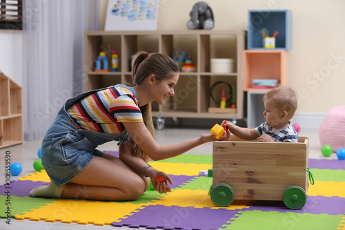 Teen nanny and cute little baby playing with toys at home photo