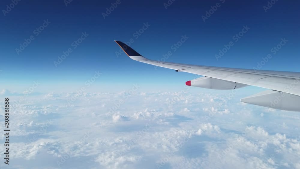 Flying airplane wing flying in the clear blue sky with clouds below. Cloudscape sky with copy space. Flying airplane wing flying in the clear blue sky with clouds below. Cloudscape sky with copy space.