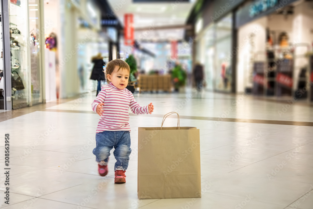 smart nature friendly shopping concept. Close up of eco friendly paper bag.  little cute baby girl run to a paper bag for shopping in the mall . soft  focus, blur background Stock