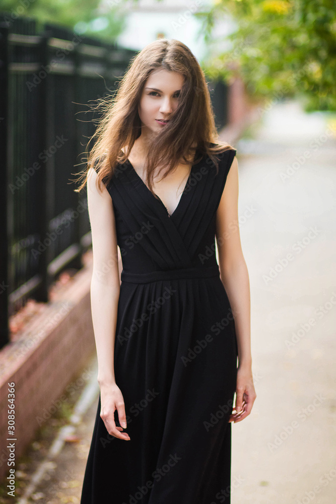 young, beautiful girl in black dress, outdoor photo on a background of steel fence, summer evening. Moddel with clean skin. young, beautiful girl in black dress, outdoor photo on a background of steel fence, summer evening. Moddel with clean skin.