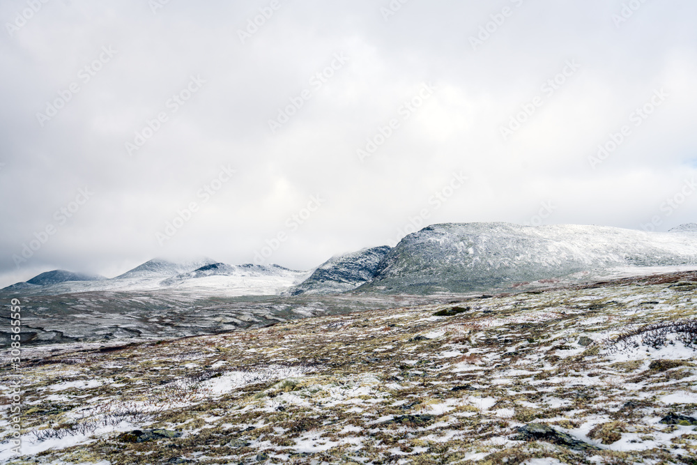 Snowy mountain peaks in Rondane national park in Norway. Snowy, foggy and frozen landscape during winter. Hiking and nature concept.