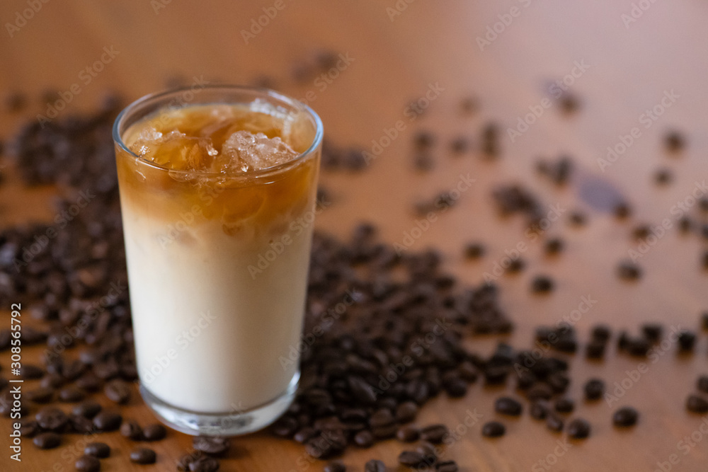 Glass with iced coffee with milk, cream with beans on a wooden background Glass with iced coffee with milk, cream with beans on a wooden background