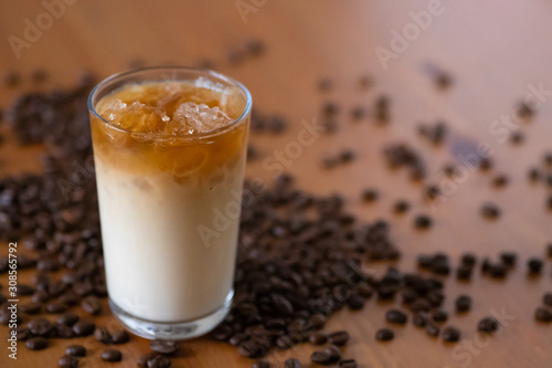 Glass with iced coffee with milk, cream with beans on a wooden background