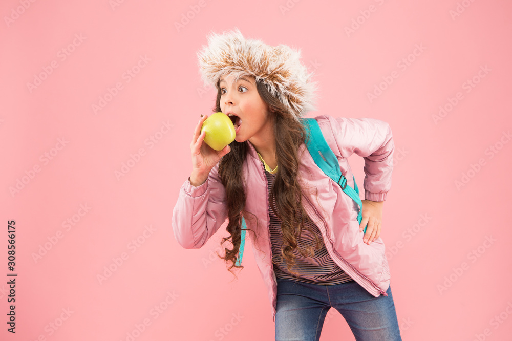 kid pink background. teen daily life. education and happy kids. schoolgirl with books after lesson. school break. small happy girl earflap hat eat apple. end of winter semester. holiday and vacation. kid pink background. teen daily life. education and happy kids. schoolgirl with books after lesson. school break. small happy girl earflap hat eat apple. end of winter semester. holiday and vacation.