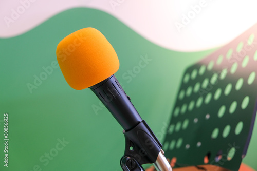 Close-up of orange head microphone in the classroom singing for children Green-white wall backdrop with book stand.