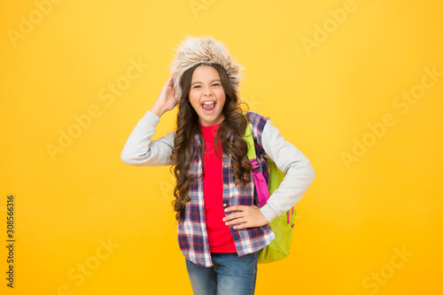 what to do during holiday. course selection period. carefree child pupil. small girl wear earflap hat. winter school time and holidays. winter courses education. schoolgirl backpack yellow background