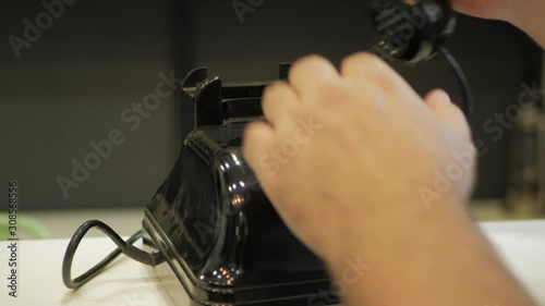 A man picking up the receiver and is trying to call on a retro telepho. photo