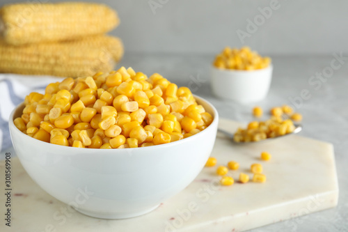 Delicious canned corn in bowl on light table, closeup