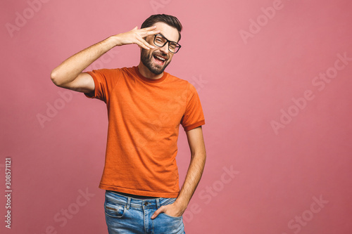 Happy young man. Portrait of handsome young man in casual smiling while standing against pink background.