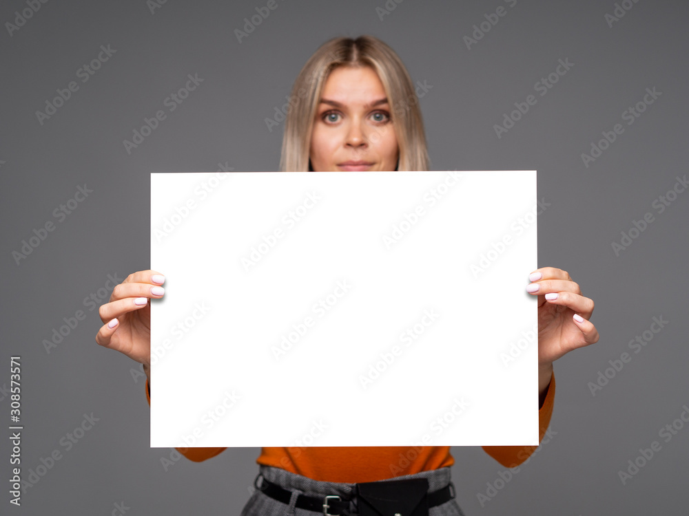 Gorgeous young woman holding a mockup vertical A1 white paper sheet with copy space for text Gorgeous young woman holding a mockup vertical A1 white paper sheet with copy space for text