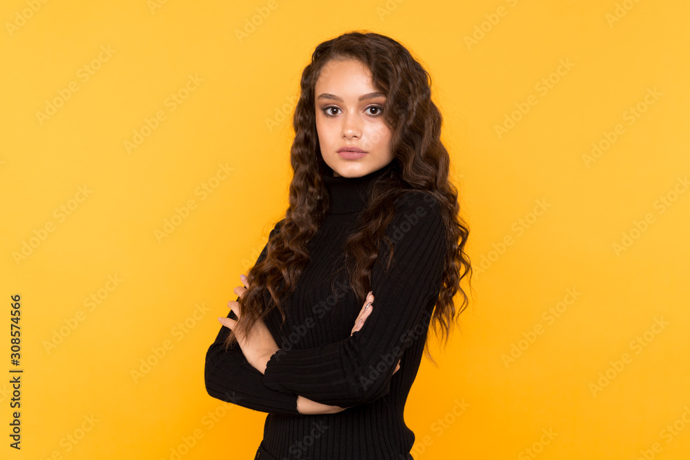 Fototapeta premium Portrait of woman in trendy black clothes standing isolated in the yellow studio