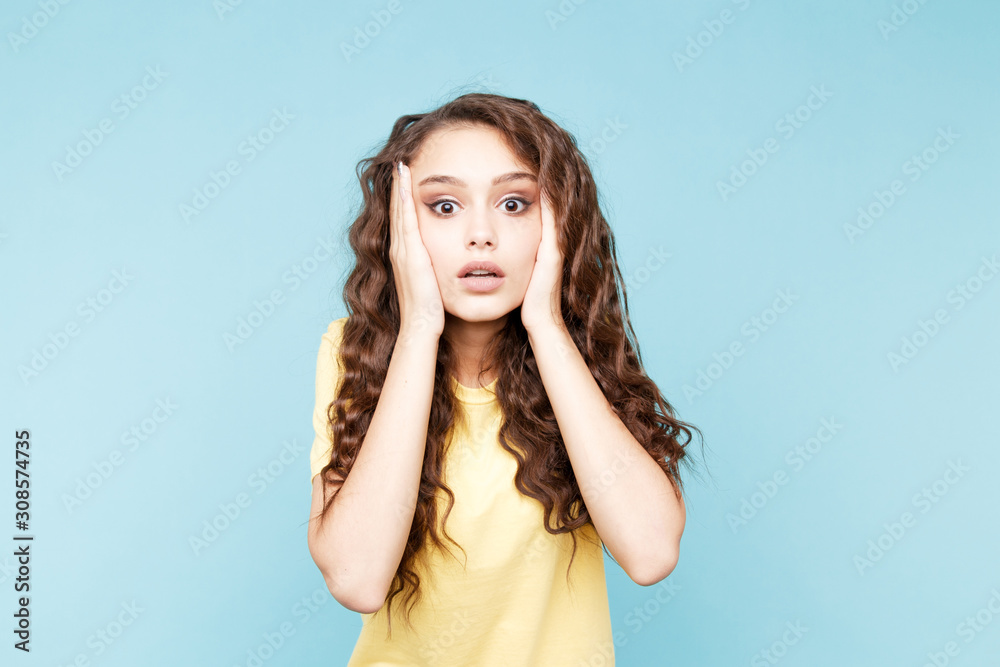 Fototapeta premium Surprised pretty woman opened her mouth and standing in the blue studio isolated