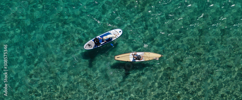 Aerial drone ultra wide panoramic photo of unidentified fit man paddling with his cute dog on a SUP board or Stand Up Paddle board in tropical exotic emerald bay
