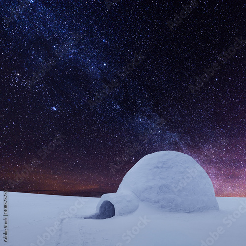 Wintry scene with snowy igloo and milky way in night sky. Fantastic winter landscape glowing by star light. Santa house from snow, ideal New Year and Christmas background