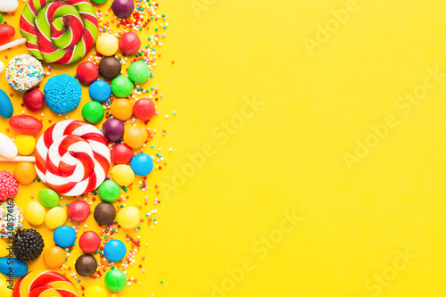 Colorful candies over yellow background. Top view. Flat lay
