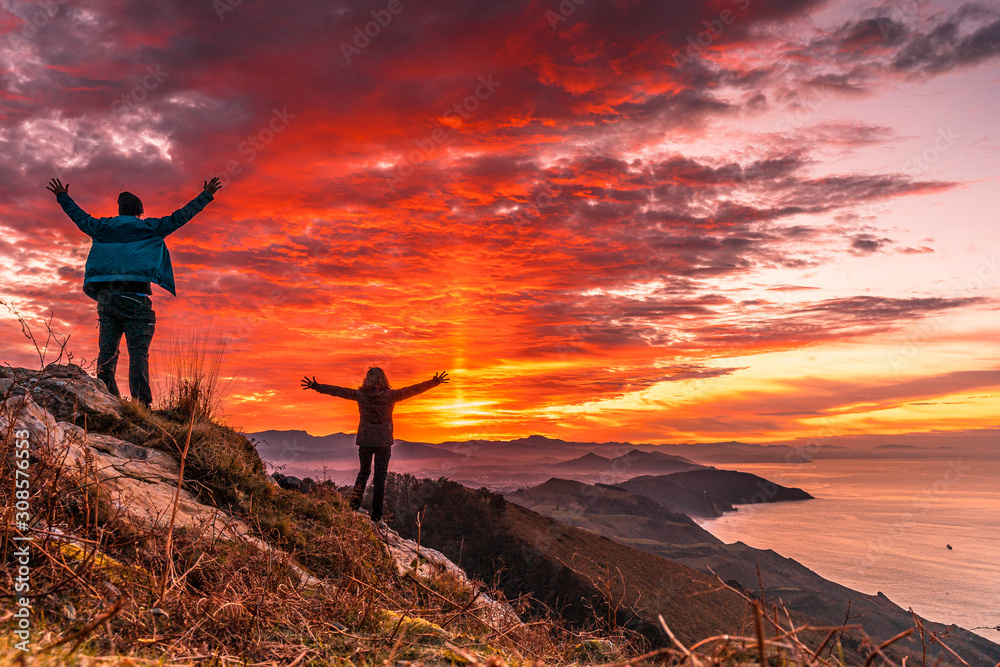 Obraz premium A couple in the incredible orange sunset on the winged Mount Jaizkibel of San Sebastian. Basque Country