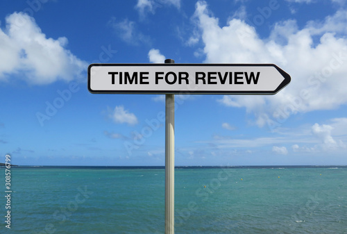 Road sign with TIME FOR REVIEW text under caribbean ocean background