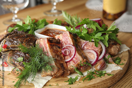 Delicious roasted ribs and liver with herbal on wooden board, closeup